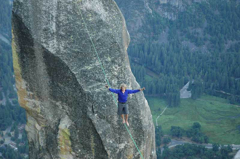 Corbin slacklining Lost Arrow Spire.  He is wearing a waistbelt harness and a safety leash, though it isn't really visible in the picture. (Category:  Rock Climbing)