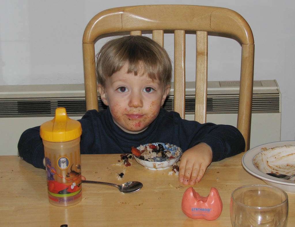 Like most toddlers, Sylvan doesn't eat food.  He just smears it on his face and absorbs the nutrients through his skin.  Is that a thyroid in the foreground? (Category:  Party)