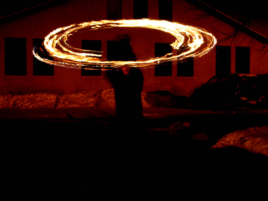 Fire juggling.  That's a 1/2 second exposure to get the fire trail like that. (Category:  Photography)