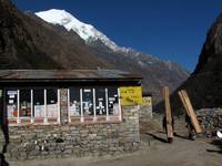 Langtang II behind Lovely Lodge.  Note the porters carrying lumber uphill. (Category:  Travel)